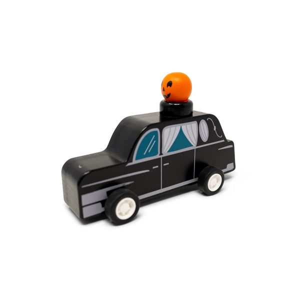 Toy black car with a pumpkin on top against a white background